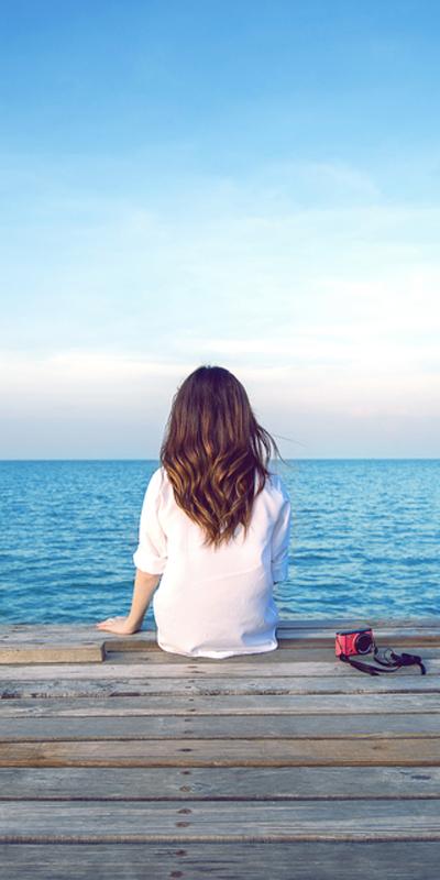 Woman sitting on her own at the end of a jetty