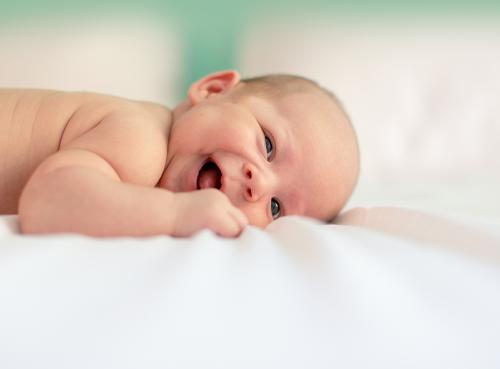 Newborn baby lying on a blanket smiling